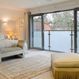 A large bedroom looking out through open doors onto a Juliet balcony