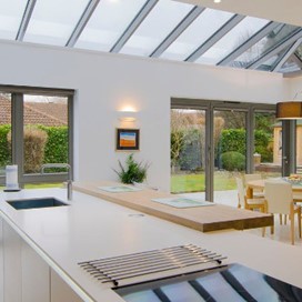 A kitchen with a glass ceiling and large bifold doors looking out onto the garden
