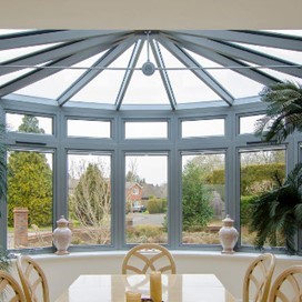 An internal view of a bay windowed dining room with a glass ceiling overhead