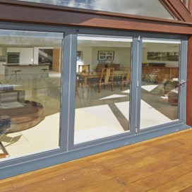 Closed patio doors viewed from the sunny terrace of a riverside property