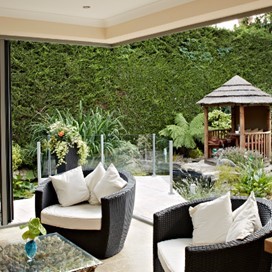 Looking out through open folding doors into a garden with a lawn and gazebo