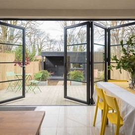 View from a dining room looking out into a garden through open bifold doors