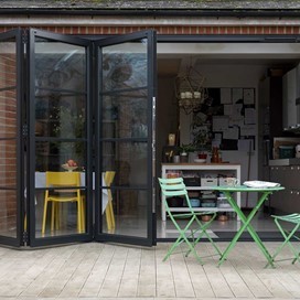 Outside looking into a modern dining room, looking through open bifold doors
