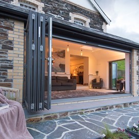 Origin bifold doors open leading into a modern and well lit dining room