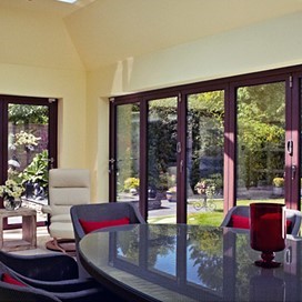 A bright house extension with a large table, comfortable chairs and large folding doors out to the garden