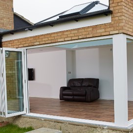 Looking into a garden room through fully opened folding doors that make up two walls of the room