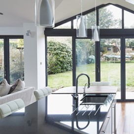 A large, modern, open plan kitchen and living area with large glass folding doors looking out to the garden