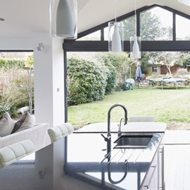 A large, bright, open plan kitchen and living area with large glass folding doors opening out to the garden