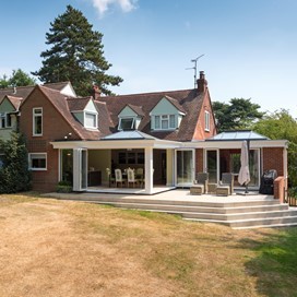 Landscape photo of the side of a house with white bifold door extension connected