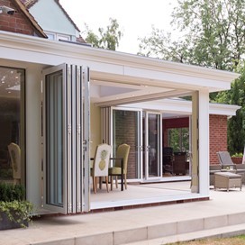 White bifold doors open from the outside revealing a set of table and chairs
