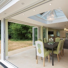 Inside of extension showing a set of chairs around a table with a open bifold door behind