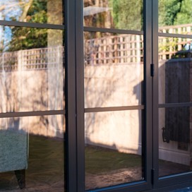 Black bifold doors reflecting the image of a outdoor garden back at the camera
