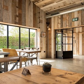 Inside a cafe with tables looking out onto a farm through bifold doors
