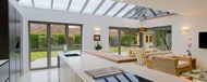 A kitchen with a glass ceiling and large bifold doors looking out onto the garden