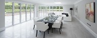 A bright dining area with large bifold doors and a corner door covering the length of the room