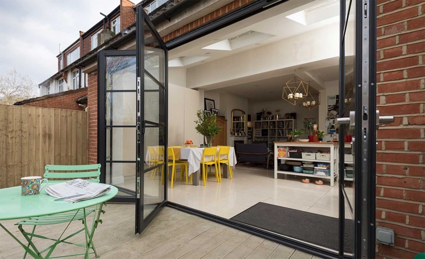 Side view from the outside of a modern dining room with a open set of bifold doors