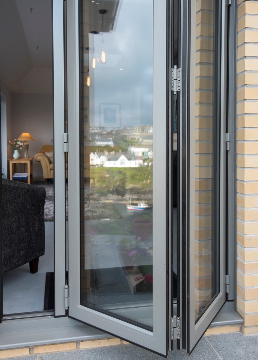 Open set of white bifold doors from the outside looking into a modern living room
