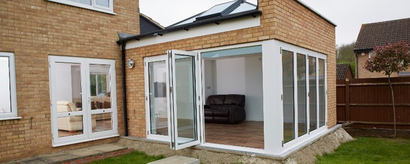 Looking into a garden room with large skylight through a partially opened folding door