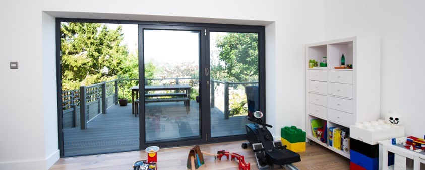 A bright room with partially opened folding doors looking out onto upper storey decking