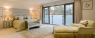A large bedroom looking out through open doors onto a Juliet balcony