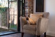 A small dog on a cream arm chair next to half open bifold doors
